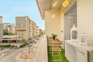 Ein Balkon mit einem kleinen Tisch, Stühlen, einem Blumentopf und einer Daikin Klimaanlage.