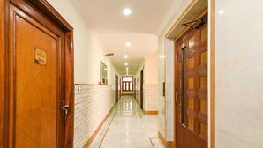 Un pasillo de hotel con puertas de madera, suelo de mármol y un cartel que indica la habitación Heritage 304.