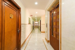 Un pasillo de hotel con puertas de madera, suelo de mármol y un cartel que indica la habitación Heritage 304.