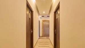 Un pasillo con puertas a ambos lados, piso de baldosas y un ascensor al final.