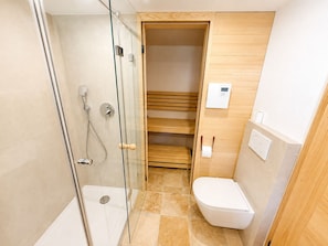 A bathroom with a glass-enclosed shower, a toilet, and a wooden shelf unit.