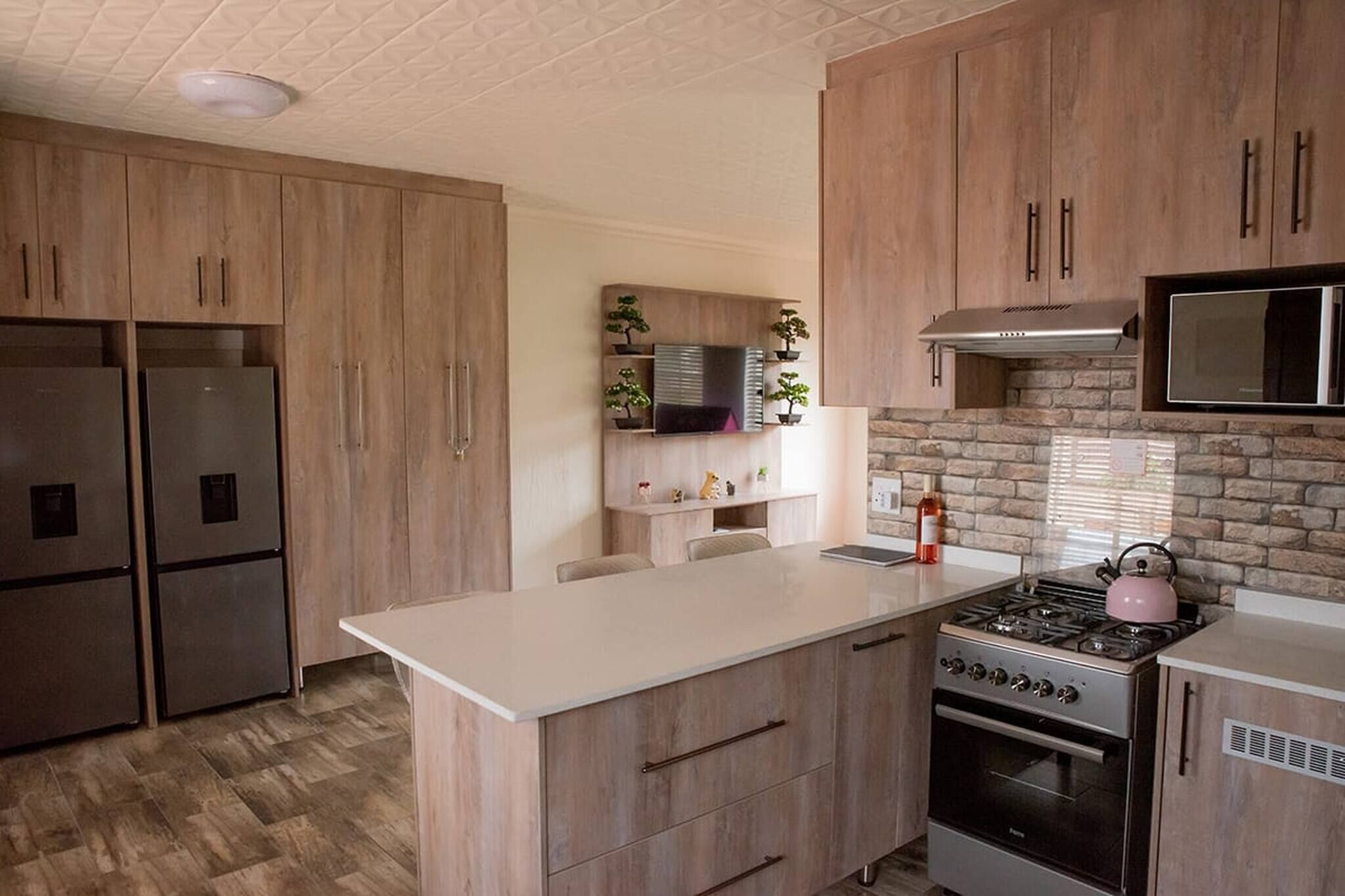 A kitchen with wooden cabinets, a built-in microwave, a stove, and a refrigerator.