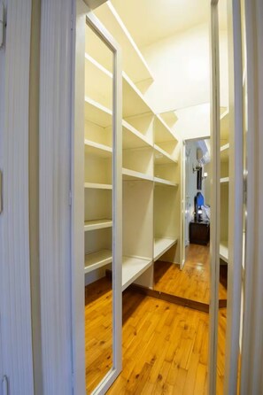 A walk-in closet with open shelving and a wooden floor. - New Cairo stylish apartment (New Cairo)