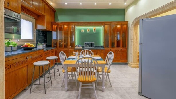 A kitchen with wooden cabinets, a dining table with chairs, and a refrigerator. - New Cairo stylish apartment (New Cairo)