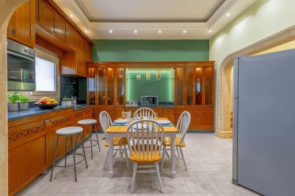 A kitchen with wooden cabinets, a dining table with chairs, and a refrigerator. - New Cairo stylish apartment (New Cairo)