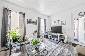 A modern living room with a flat-screen TV, seating area, and a glass coffee table.