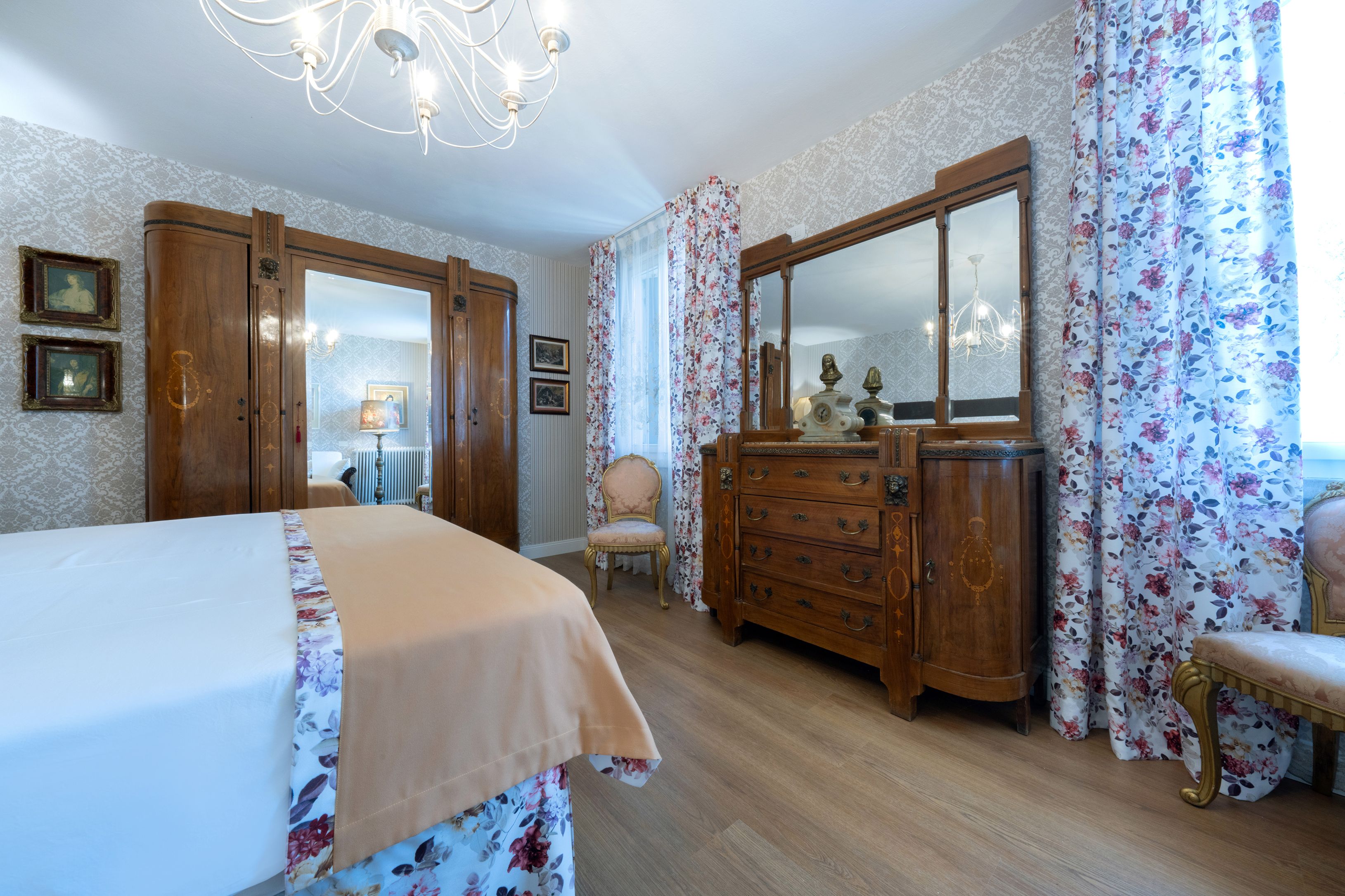 Une chambre à coucher comprenant un lit, une commode, une chaise et un grand miroir.