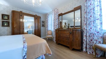 Ein Schlafzimmer mit einem Bett, einer Kommode, einem Stuhl und einem großen Spiegel.