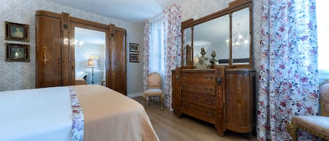 A bedroom with a bed, a dresser, a chair, and a large mirror.