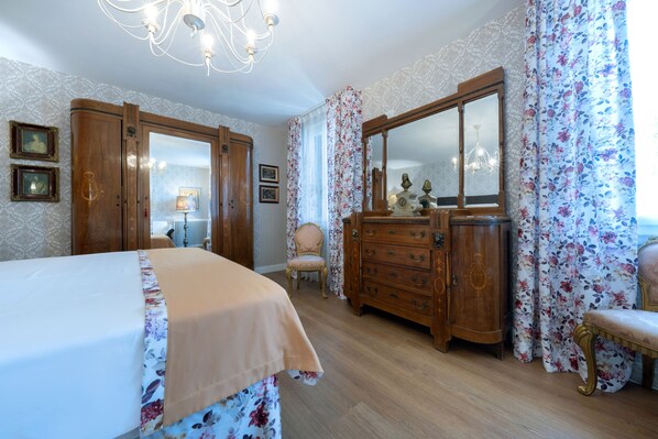 A bedroom with a bed, a dresser, a chair, and a large mirror.