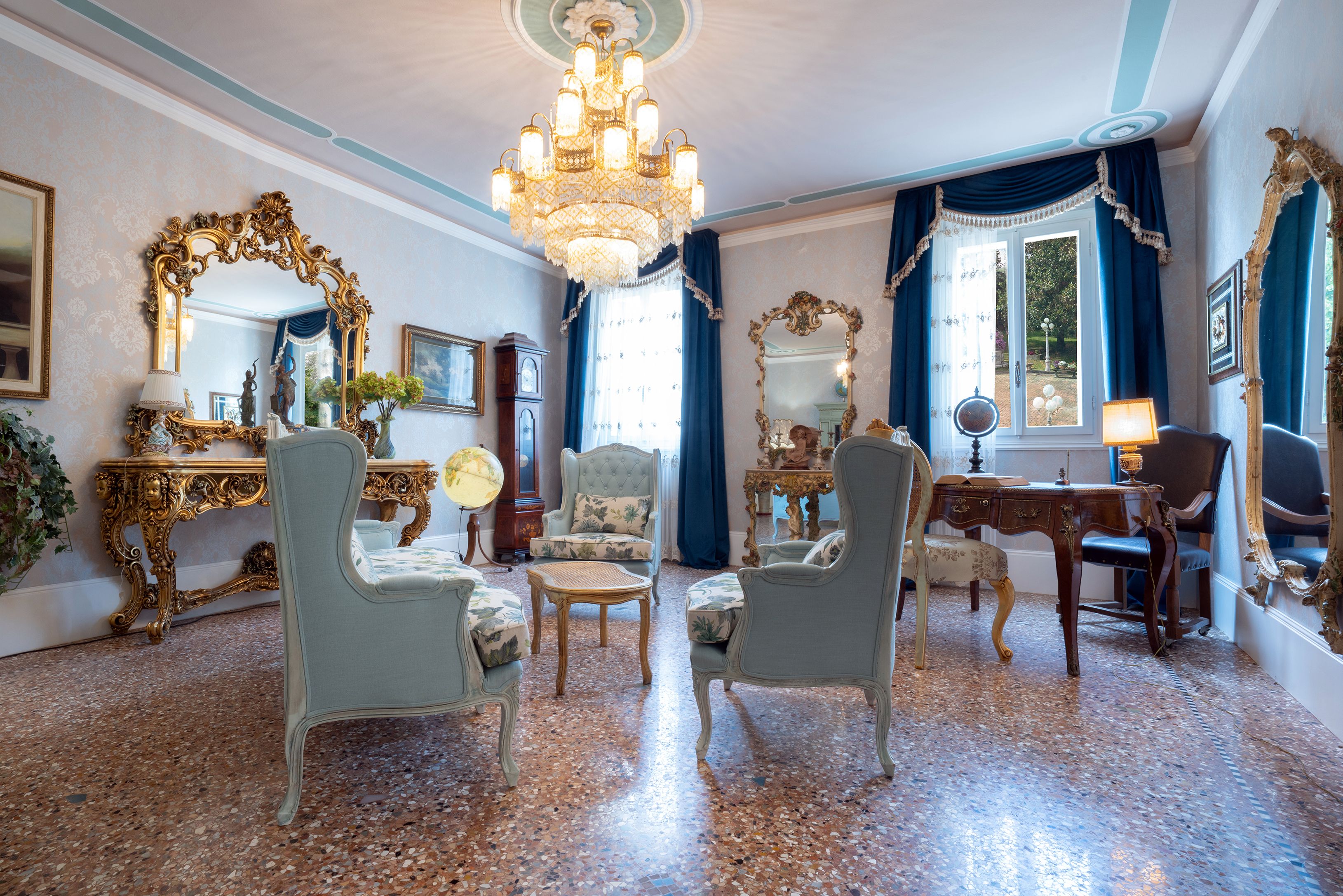 Una habitación con candelabro, muebles ornamentados y un espejo grande.