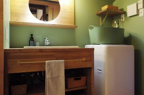 A bathroom with a wooden vanity, a mirror, a sink, and a green basin. - ITAKURA KF1 (Kitakyushu)