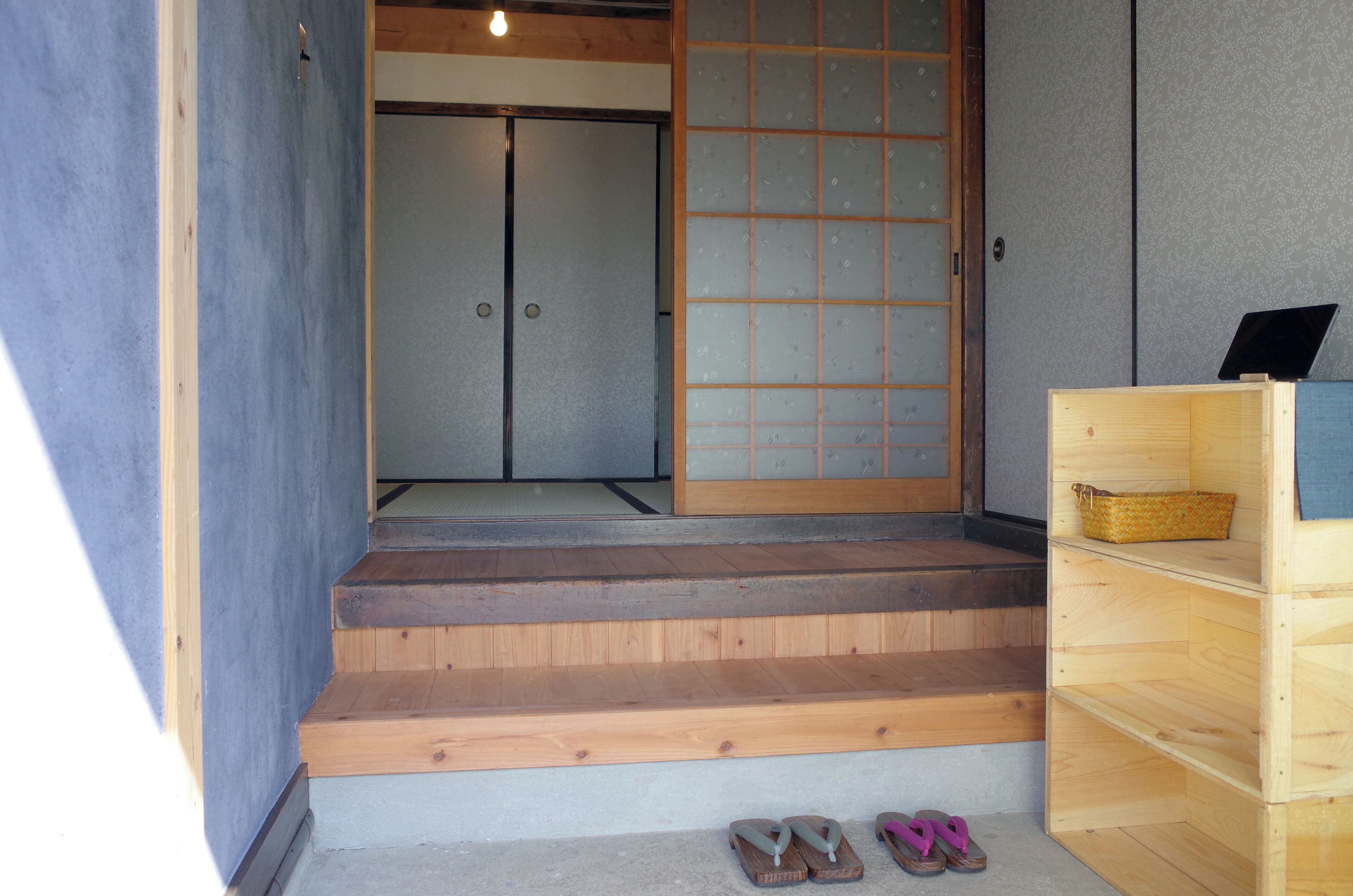A wooden staircase leading to a room with a sliding door and a small wooden shelf with a basket.