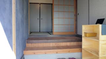 A wooden staircase leading to a room with a sliding door and a small wooden shelf with a basket.