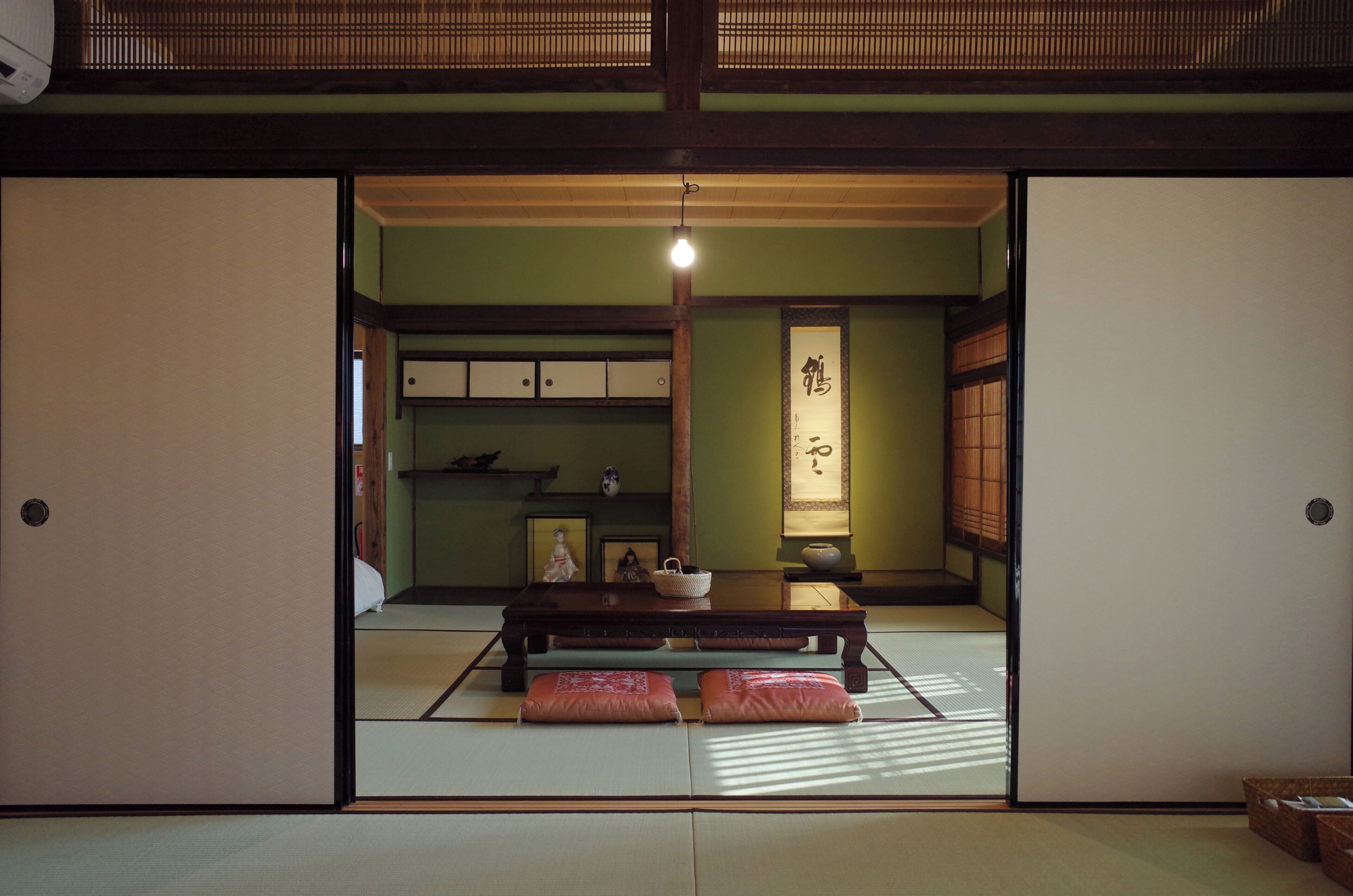A traditional Japanese room with tatami flooring, a low table with cushions, sliding doors, and a shoji screen.