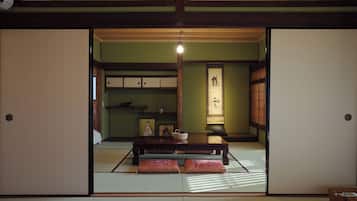 A traditional Japanese room with tatami flooring, a low table with cushions, sliding doors, and a shoji screen.