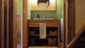 A bathroom with a wooden vanity, a mirror, a towel hanging on a rack, and storage baskets.