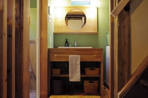 A bathroom with a wooden vanity, a mirror, a towel hanging on a rack, and storage baskets.