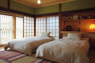 Un dormitorio de estilo japonés tradicional con dos camas, suelo de estera de tatami y una puerta corrediza de shoji.
