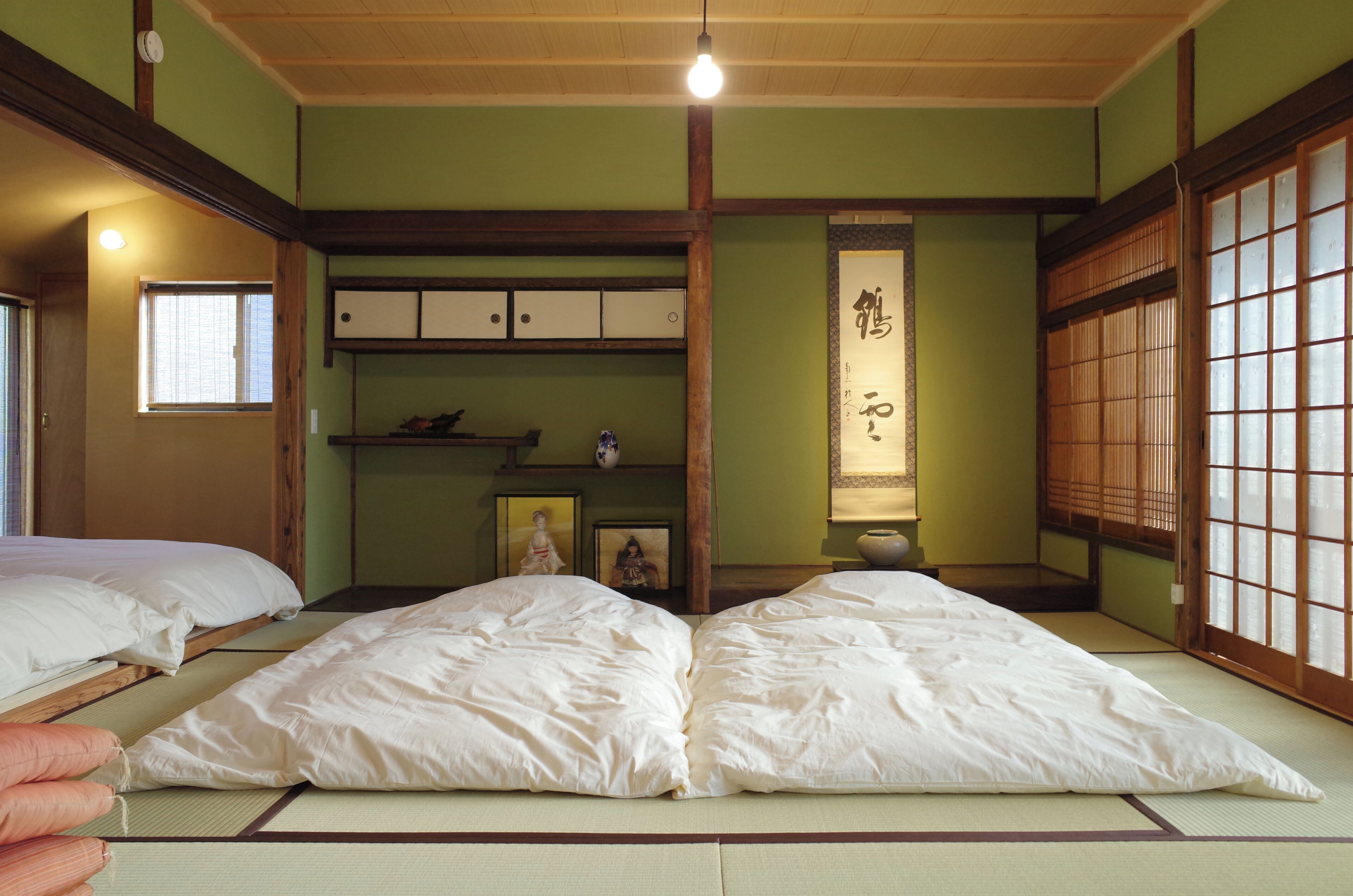 Ein traditioneller japanischer Raum mit Tatami-Böden, niedriger Holzdecke, Schiebetüren und einem Shoji-Bildschirm.