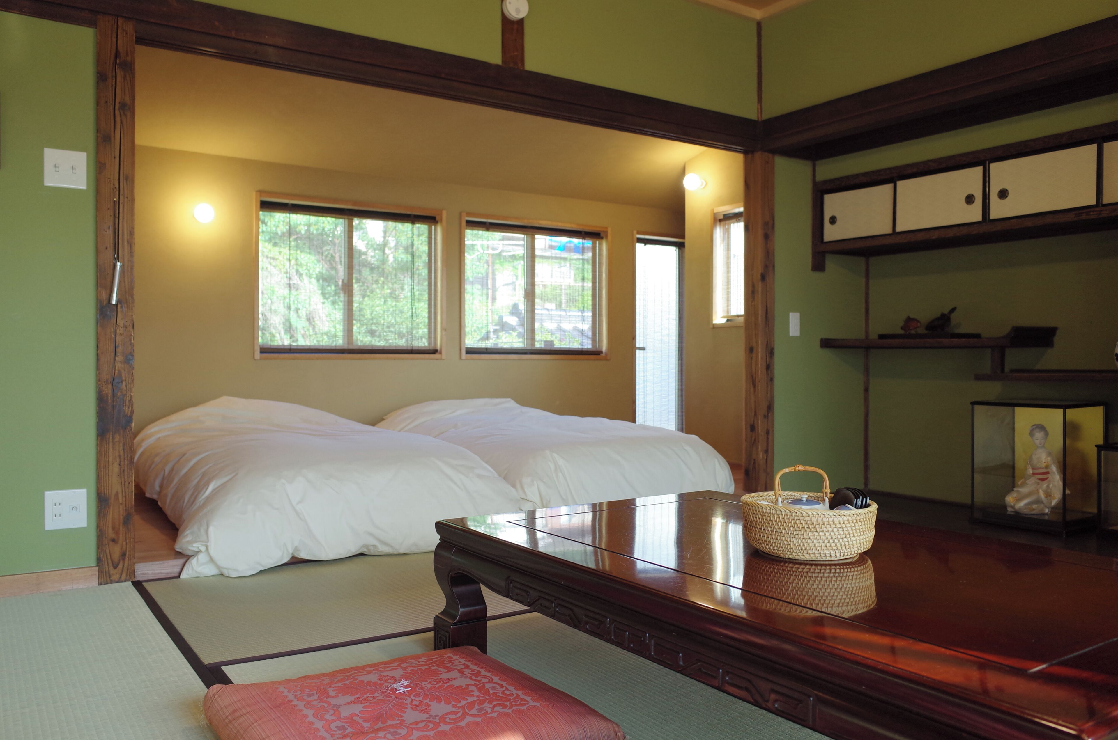 A traditional Japanese-style room with a bed, tatami flooring, and a wooden table with a woven basket.