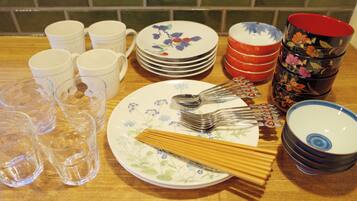 A table with various kitchenware items including plates, cups, and utensils.