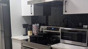 A modern kitchen with stainless steel appliances, white cabinetry, and a black countertop.