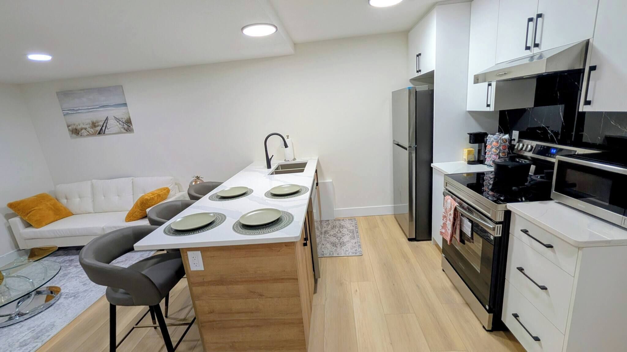 A modern kitchen with white cabinets, a stainless steel refrigerator, and a black microwave.