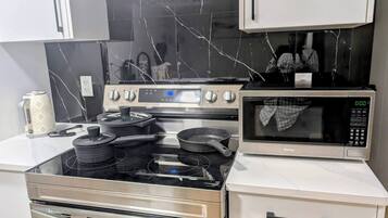 A kitchen with a stainless steel stove, a microwave, and a marble backsplash.