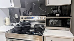 A kitchen with a stainless steel stove, a microwave, and a marble backsplash. - Sweet Home Escape 2BR guest suite (Edmonton)