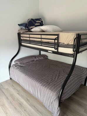 A bunk bed with a lower bunk and a mattress on the floor.