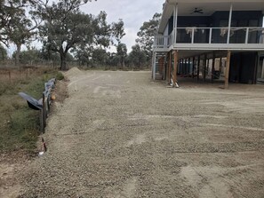 A gravel driveway leading to a building with a balcony.