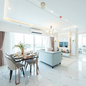 A modern living room with a dining area, a sofa, a TV, and a chandelier. - Sea View Unit I 2 Bed Room I Near The Beach (Muang Pattaya)