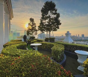 A rooftop garden with manicured hedges, a few trees, and a cityscape in the background. - Sea View Unit I 2 Bed Room I Near The Beach (Muang Pattaya)