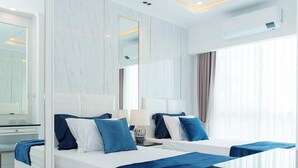 A modern hotel room with a large bed, bedside tables, a desk, and a large mirror. - Sea View Unit I 2 Bed Room I Near The Beach (Muang Pattaya)