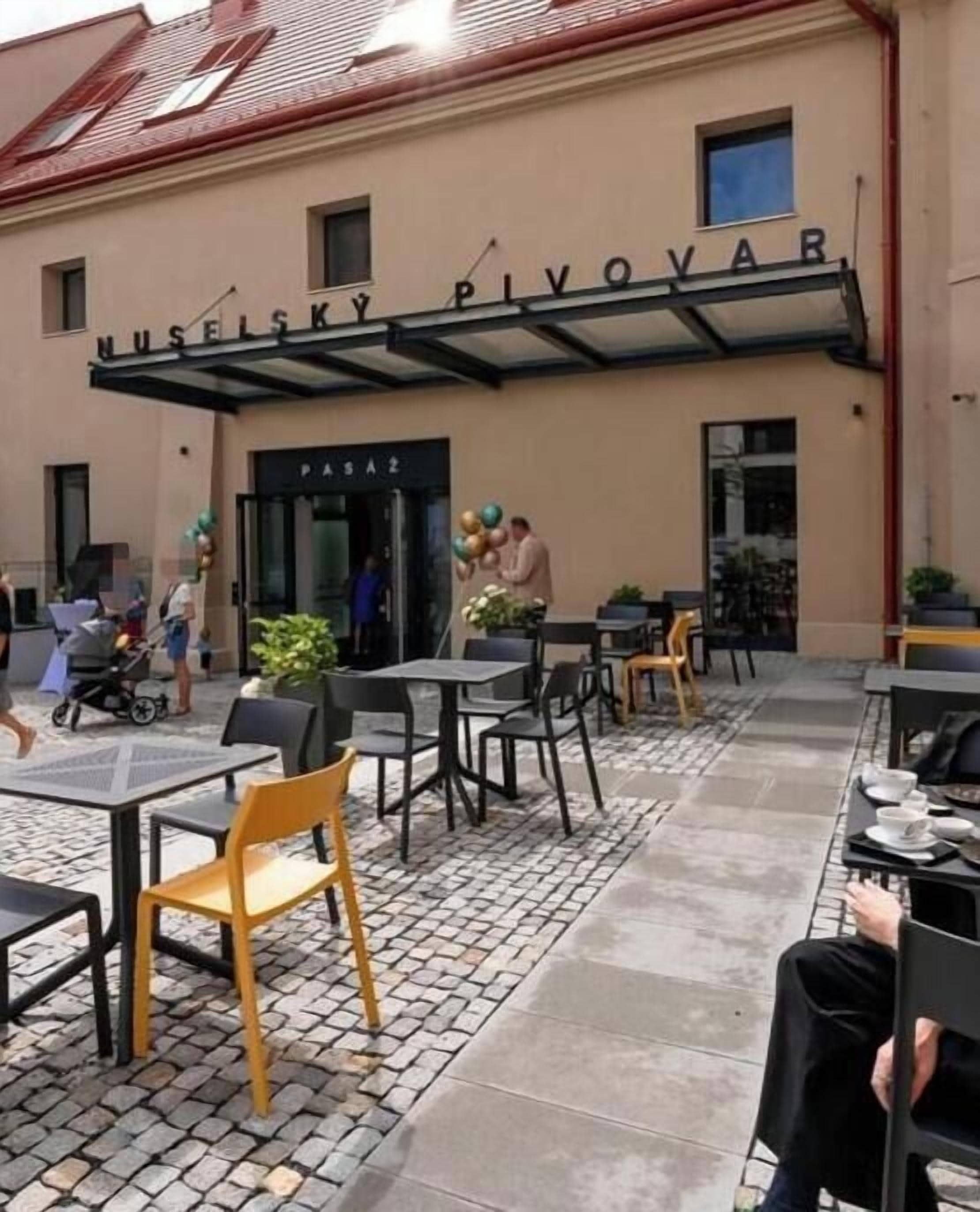 Un espace extérieur aménagé avec des tables et des chaises, une entrée couverte et un bâtiment doté d’une enseigne.
