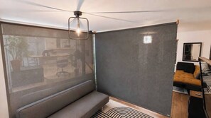 A modern room with a ceiling fan, a sofa, a coffee table, and a large window with a view. - Large urban apartment with steam sauna 1 (Montreal)