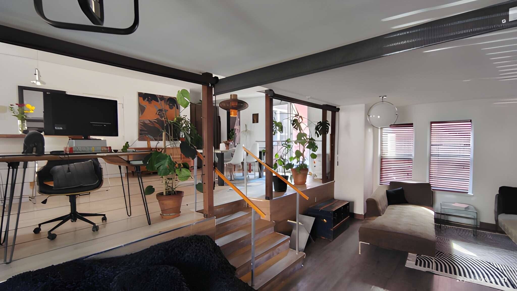 A modern living space with a staircase, a dining area, and a seating area.