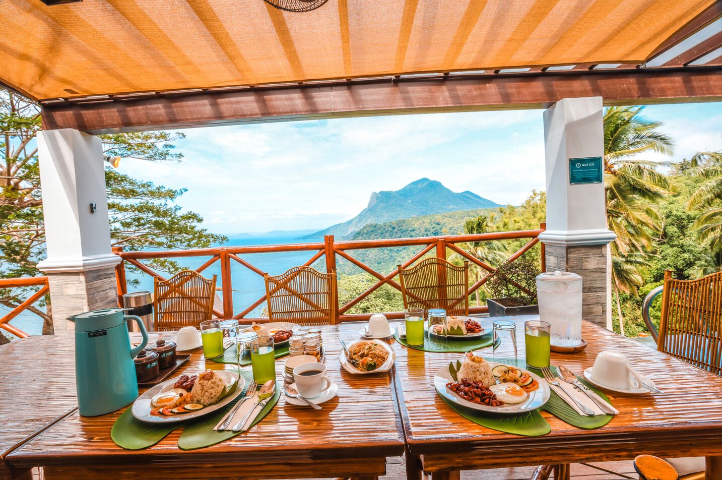 A dining table set outdoors with a view of a mountain and ocean.