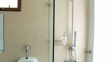 A modern bathroom with a urinal, a glass shower enclosure, and a handheld showerhead.