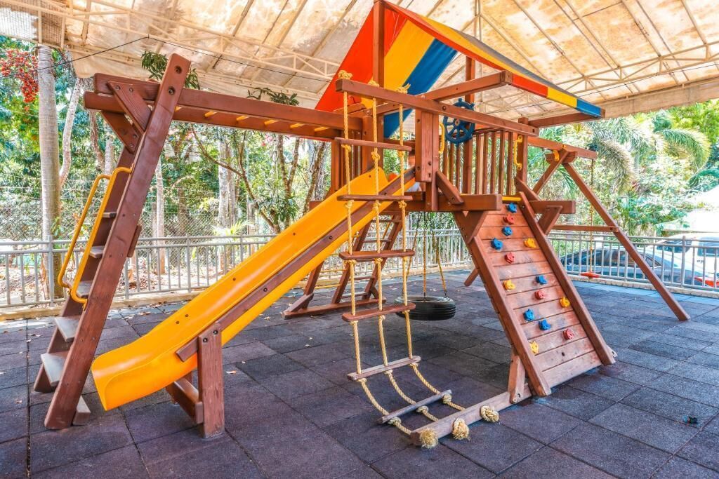 A playground with a slide, climbing net, and a tire swing.