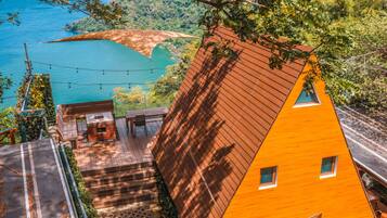 A modern house with a sloped roof, a deck, and a view of a lake.