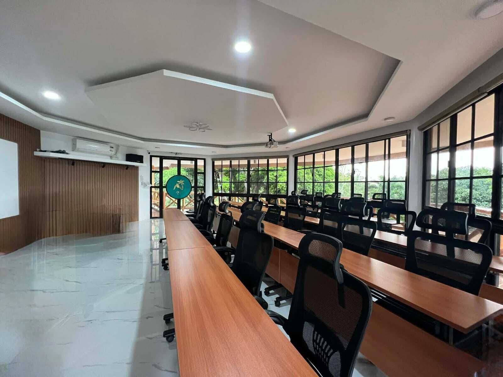 A conference room with a long table, chairs, and large windows.