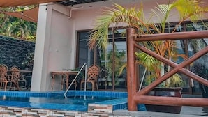 Un edificio moderno con piscina, mobiliario exterior y palmeras.