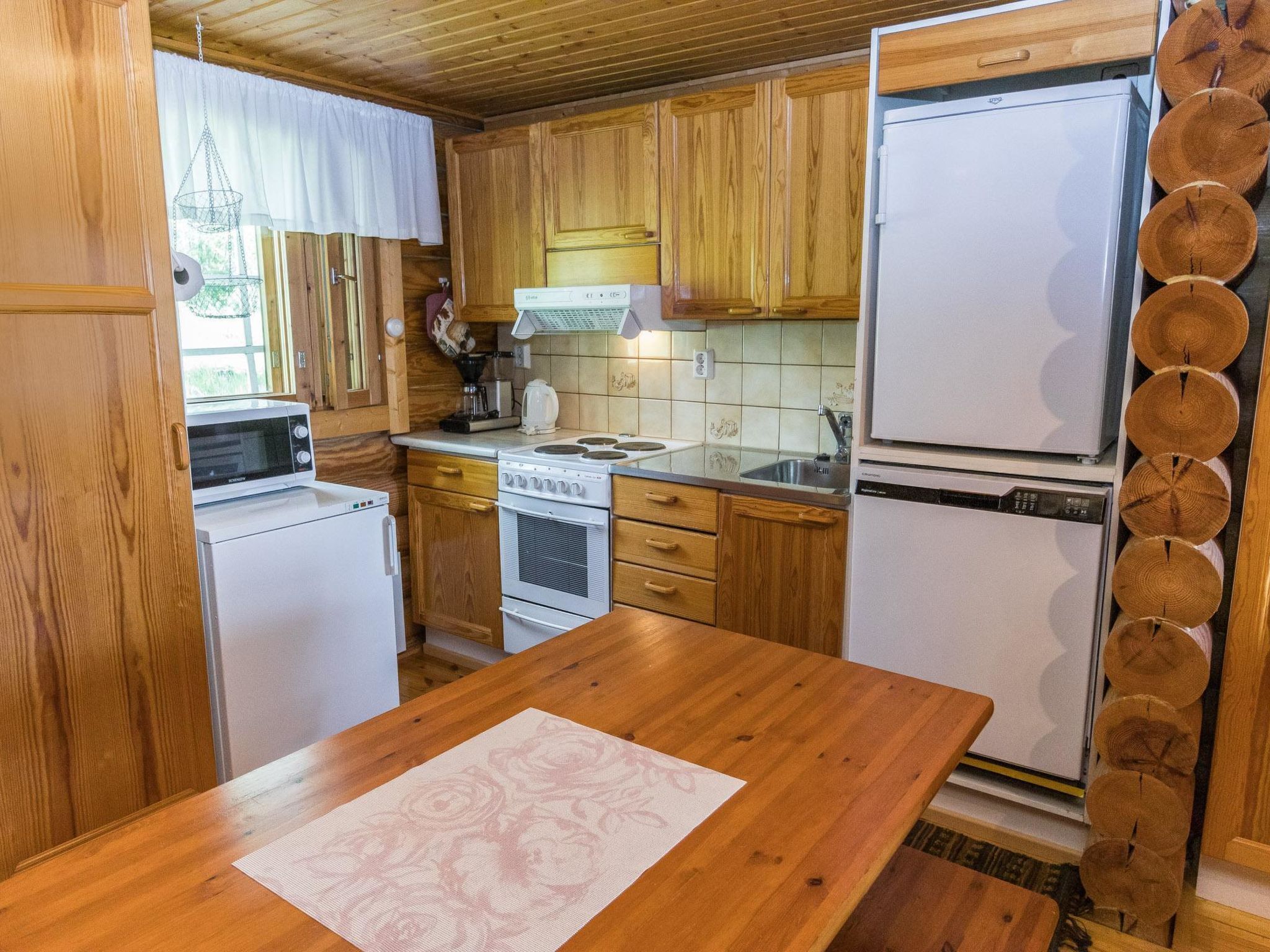 Una cocina compacta con armarios de madera, microondas, estufa y refrigerador.