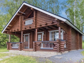 Hirsimökki, jossa on kuisti, ovi ja ikkunat.