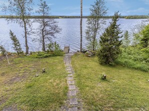 A pathway leading to a dock over a calm lake, surrounded by trees and grassy areas.