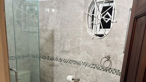 A bathroom with a glass shower enclosure, a toilet, a sink, and a decorative window. - Plantation Villa with Pool-5-Min Walk to Plantation Cove, near by beach access. (Plantation Village)