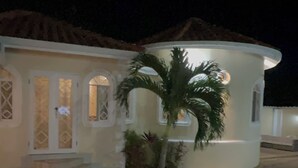A building with a pool, a palm tree, and a well-lit entrance. - Plantation Villa with Pool-5-Min Walk to Plantation Cove, near by beach access. (Plantation Village)