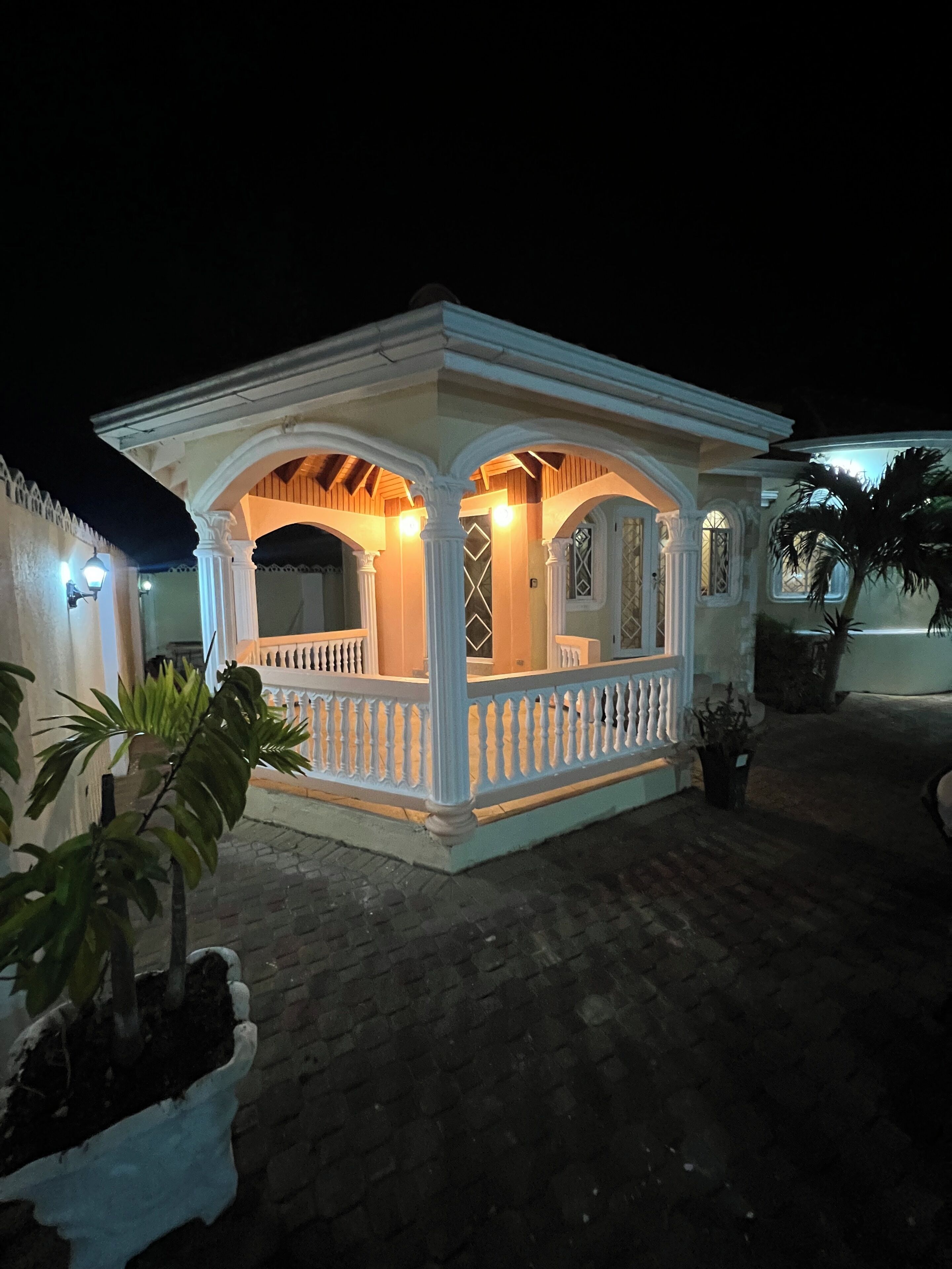 A small, white, two-story building with a balcony and a covered porch area.
